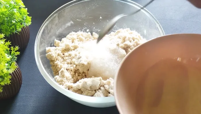 Gradually add the sugar-water mixture to the flour mixture. Mix until a firm, slightly crumbly dough forms. Do not overmix or knead it smoothly.
