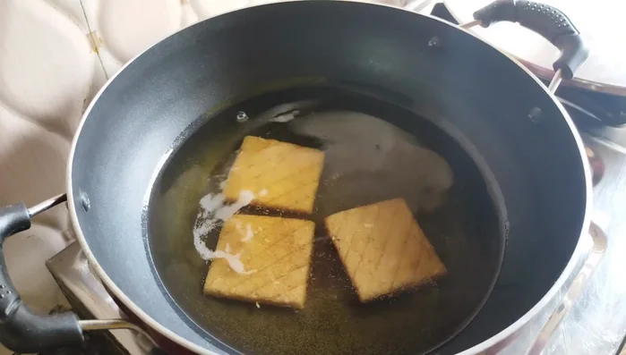 Heat oil in a pan over low heat. Fry the biscuits until golden brown, flipping halfway, ensuring they are cooked through and not raw inside.