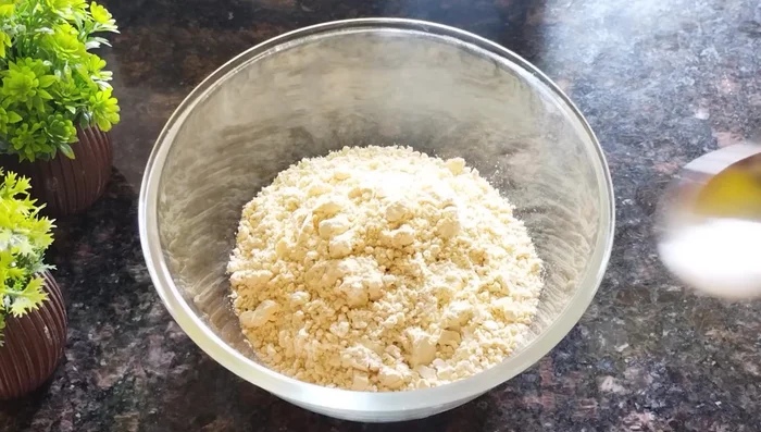 Prepare the sev batter: In a bowl, combine 2 cups of gram flour, salt, red chili powder, turmeric powder, and 2 tablespoons of oil. Mix well.