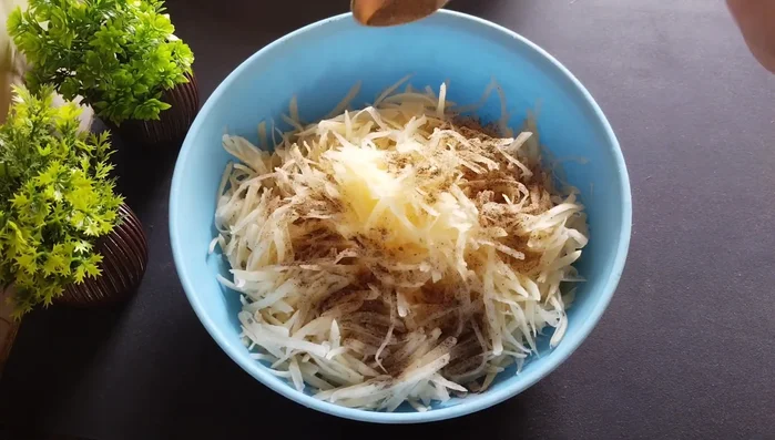 Add salt, black pepper powder, and corn flour to the grated potatoes. Mix thoroughly until well combined and the potatoes become soft.