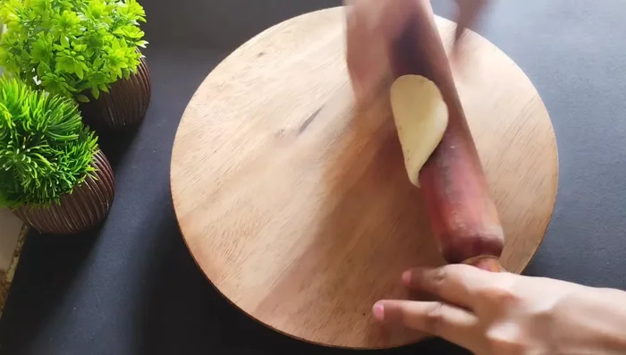 Cut each rolled dough in half to create two samosa shapes. Fill each with potato masala and seal carefully with water.