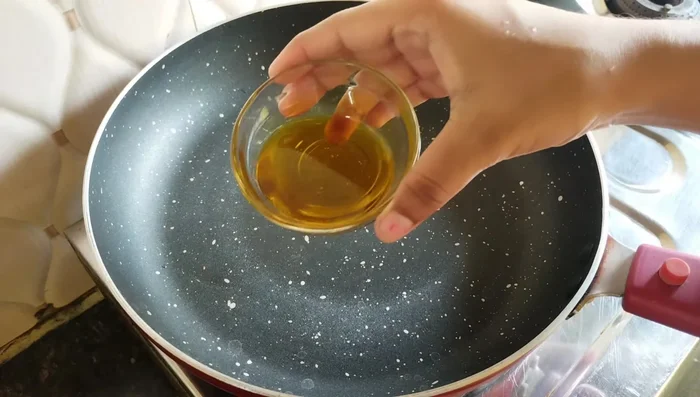 Heat mustard oil in a wok. Add panchphoran, red chilies, and cook for 2-3 minutes.