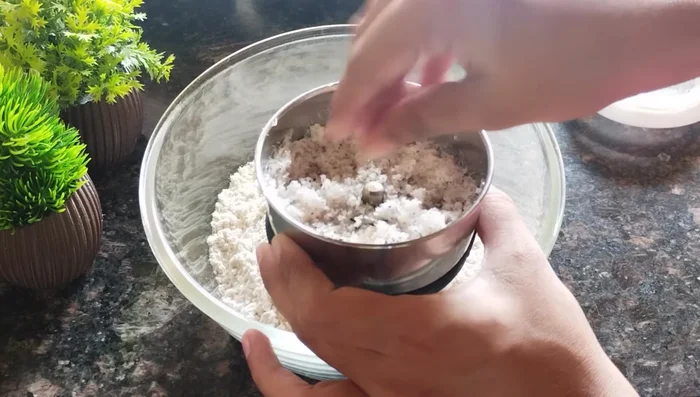 Grind dry coconut in a mixer jar. Desiccated coconut powder can be substituted.