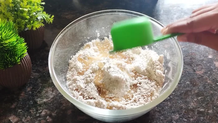 Add 1/4 cup of refined oil (or ghee) to the flour mixture and rub it in well until it resembles ladoo crumbs.