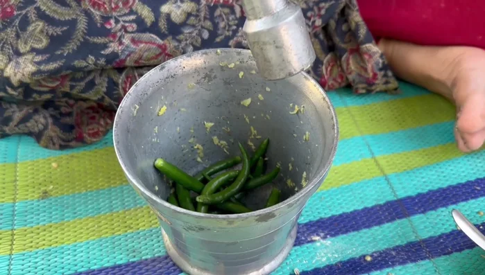 Grind green chilies with a little salt in a mortar and pestle.