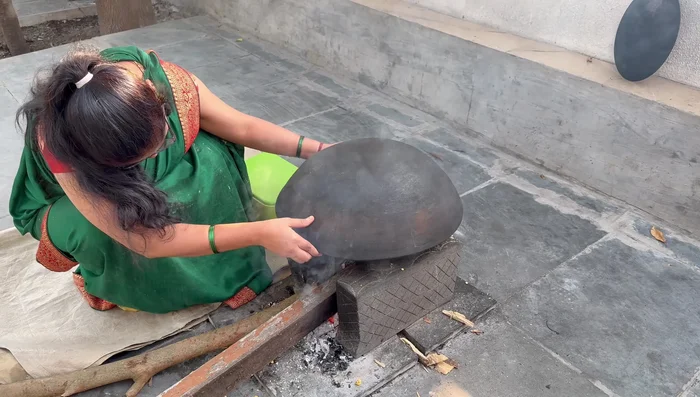 Cook the puran mande: Heat a khapar (flat griddle). Gently place the puran mande on the hot surface and cook on both sides until golden brown and crispy.