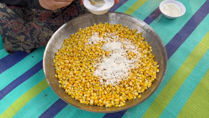 Once the corn is cool, add flour, cornflour, ginger-garlic paste, and black pepper paste to the corn. Mix well with your hands until the corn is evenly coated.