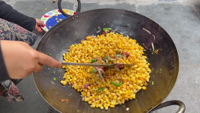 Add the fried corn kernels to the vegetables, mix well, and cook for 1-2 minutes.