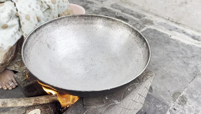 Once the cooker has released steam, heat oil in a kadai (wok). Add mustard seeds, cumin seeds, and a piece of cinnamon.