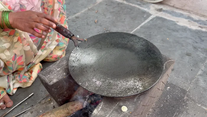 Heat oil on a tawa (iron skillet).