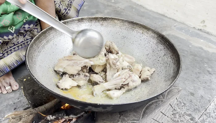 Once the chicken is cooked, add the chili flakes, crushed ginger, and green chilies.