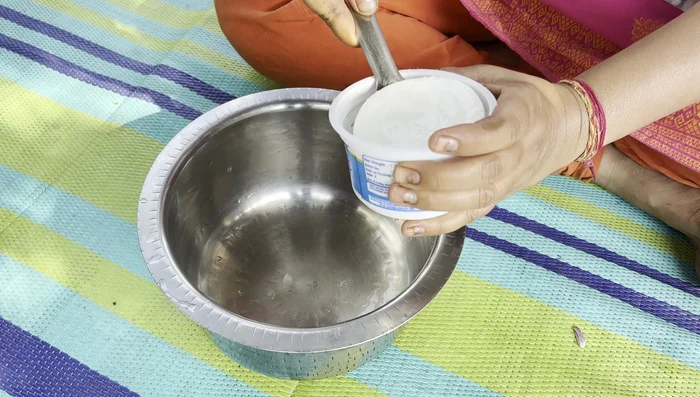 In a pan, gently beat the curd.