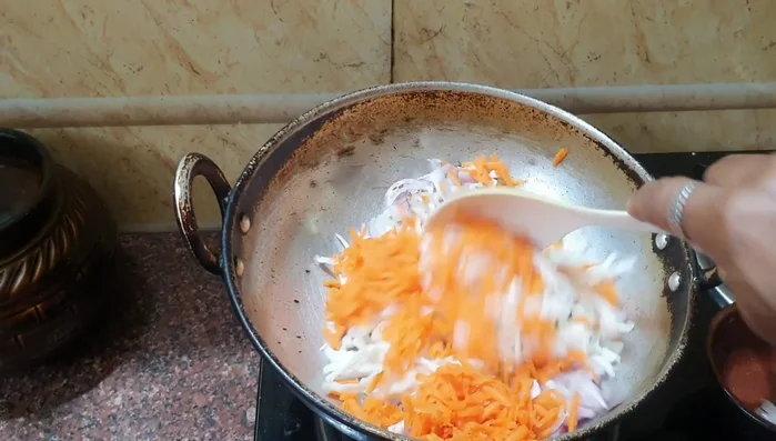 Add grated cabbage and carrot. Stir in salt, turmeric powder, coriander powder, and garam masala. Mix well.