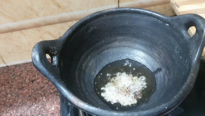 Heat oil in a pan. Add mustard and cumin seeds, then grated garlic and red chilies.