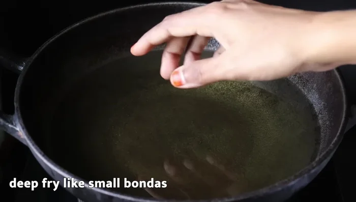 Heat ghee in a pan and start preparing the boondhi by dropping small portions of the batter into the hot ghee.