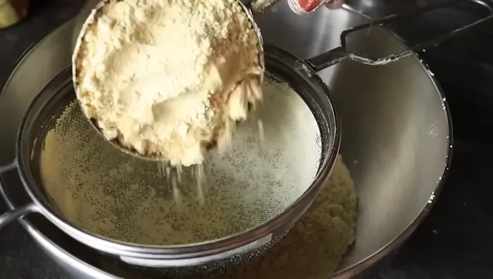 Prepare Boondi: Mix water, baking soda, baking powder, and food coloring. The exact amount of each is unclear. Fry the boondi mixture until golden brown.