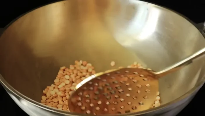 In a separate pan, heat oil and add mustard seeds. Once they splutter, add dried red chilies and curry leaves.