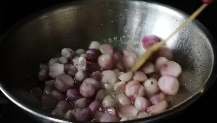 Add small onions and fry well. Add garlic cloves, salt, and continue frying.
