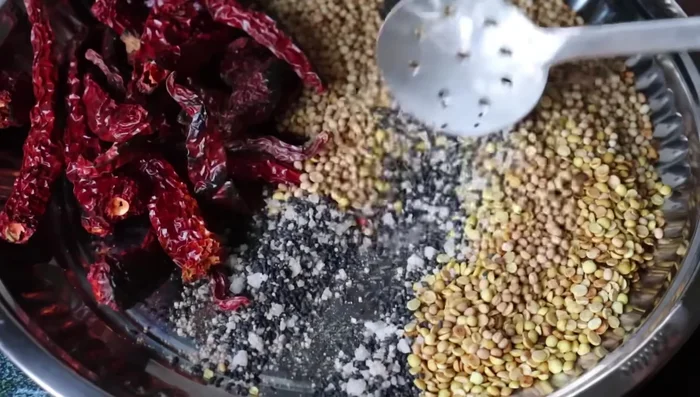 Add the fried sesame seeds, turmeric powder, and salt to the urad dal mixture. Mix well and let it cool completely.
