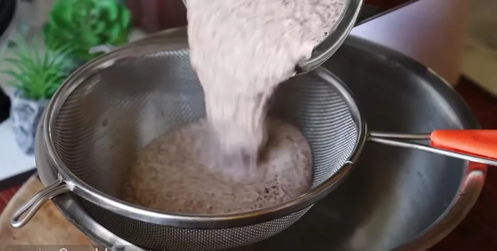 Strain the ragi paste through a sieve. Repeat the grinding and straining process 2 more times to extract maximum milk.