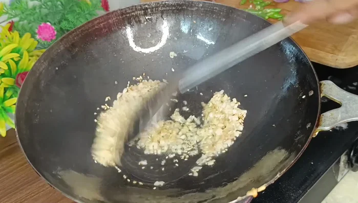 Heat oil in a pan. Add sesame seeds, minced ginger and garlic, and green chilies. Stir-fry briefly.