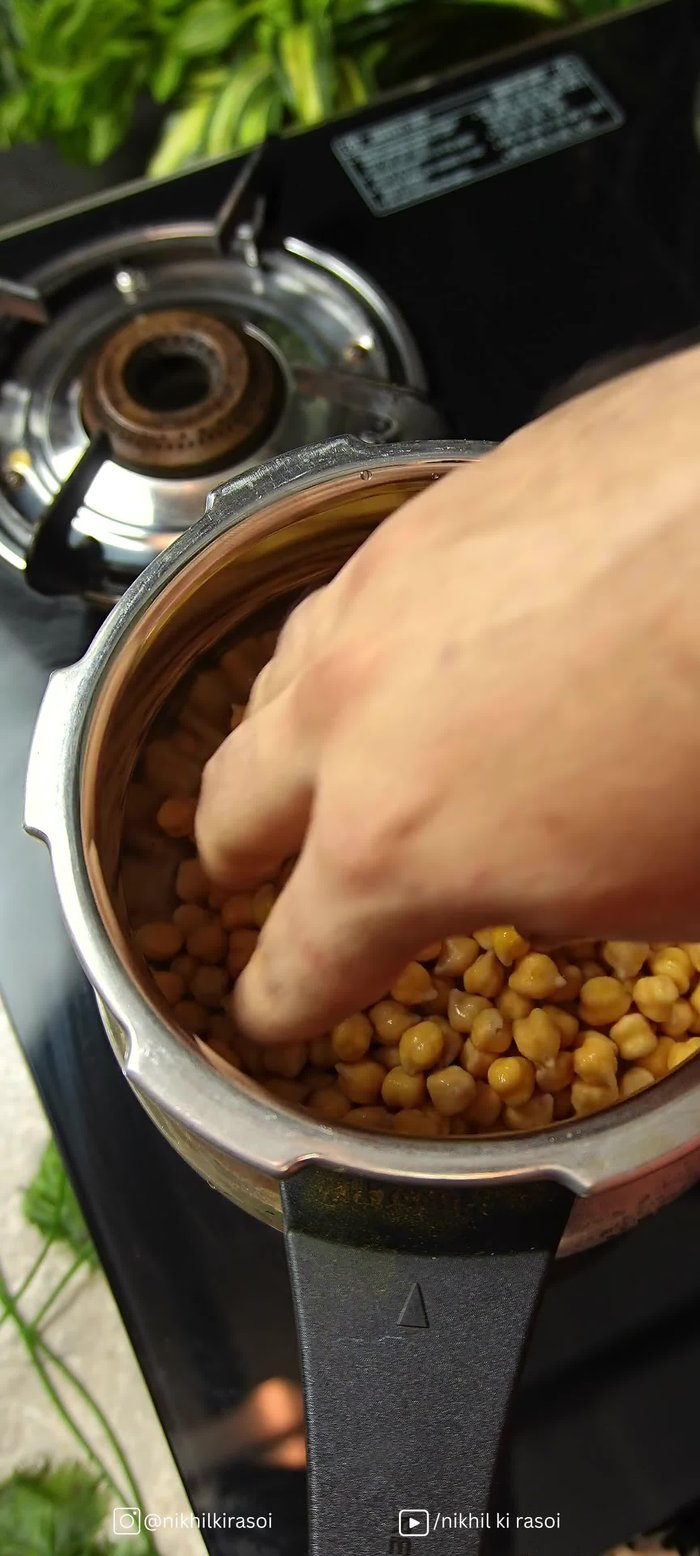 Pressure cook soaked chickpeas with garlic, celery, whole spices, salt, and pomegranate peel for 3-4 whistles.