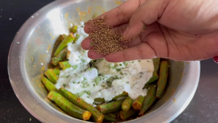 Add curd, ginger-garlic paste, roasted kasuri methi, celery (lightly crushed), dry mango powder (optional), lemon juice, black salt, white salt, and the chopped chilies and onions to the ladyfingers. Mix well.