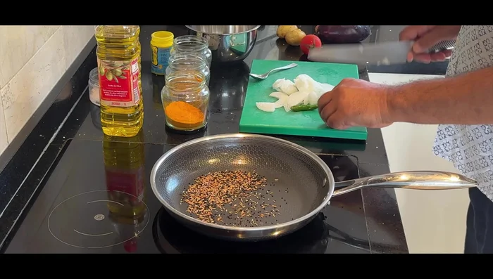 Prepare the vegetable curry: Heat oil in a pan. Add fenugreek, onion, and cumin seeds. Once the oil is released, add hing, onions, and green chilies. Add salt to release water from onions and then add tomatoes. Let it soften.