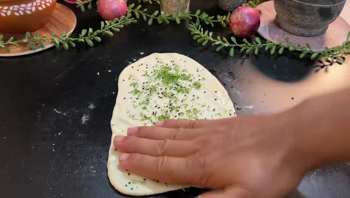 Add nigella seeds and coriander to Naan before cooking. Cook on an iron pan, first cooking the back side then the front.