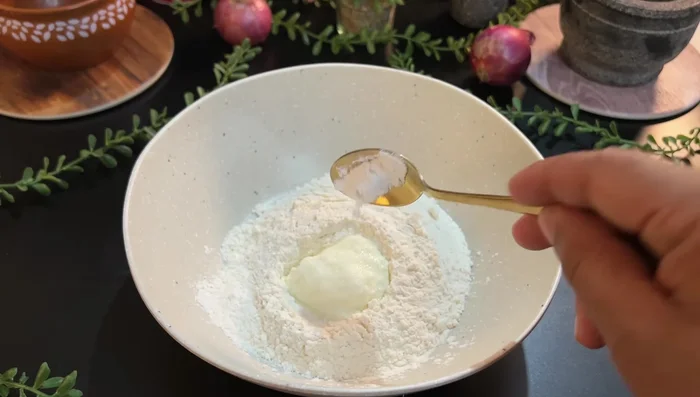 For Naan, mix flour, curd, salt, baking soda, oil, and milk. Knead well, add oil, and rest for 15 minutes. Make peda and whisk gently before cooking in a tandoor or on an iron pan.