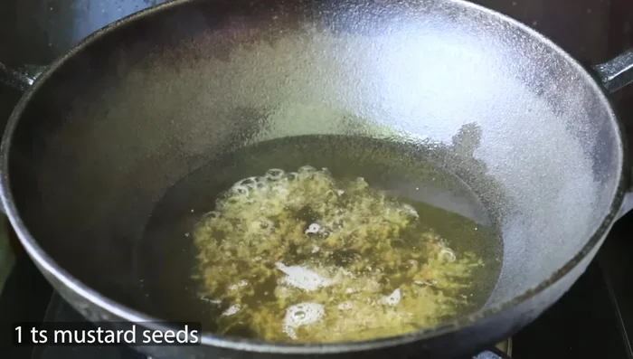 After the mustard seeds splutter, add finely chopped red chilies. Remove most of the chili seeds to reduce spiciness.