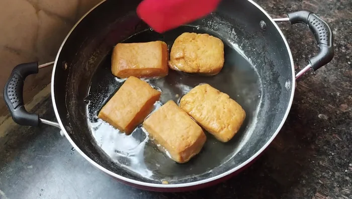 Immediately after frying, add the hot Goja pieces to the slightly warm syrup. Stir well and let them soak for 5-6 minutes.