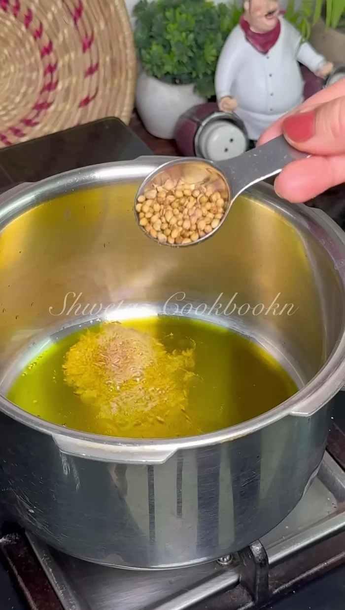 Heat mustard oil in the cooker. Temper with cumin seeds, whole coriander, and one bay leaf.