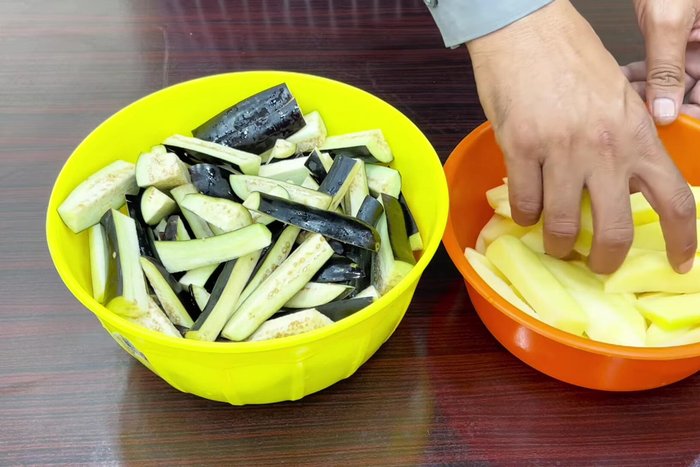 Wash and cut the brinjals and potatoes lengthwise.