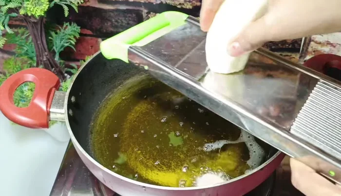 Heat oil in a pan. Using a chips cutter (or a knife), slice the peeled bananas thinly. Fry the slices in hot oil, until they are about 30% cooked.