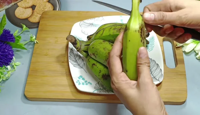 Wash and thoroughly wipe 1 kg of green bananas with a dry cloth. Trim the top and bottom of each banana.