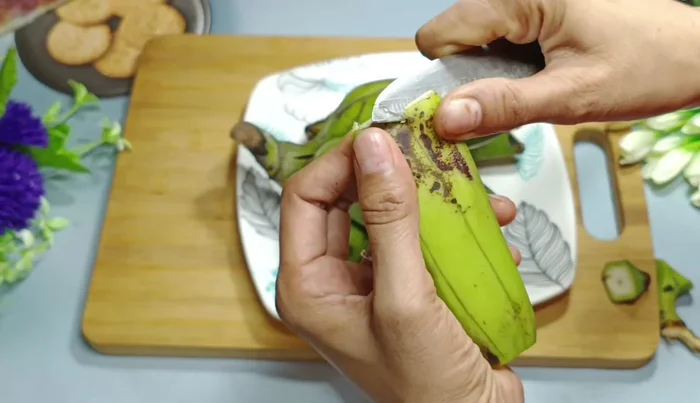 Make shallow cuts along the length of the banana, stopping just before you reach the inside flesh. Gently press to separate the peel from the banana. This avoids any green parts remaining on the peeled banana.