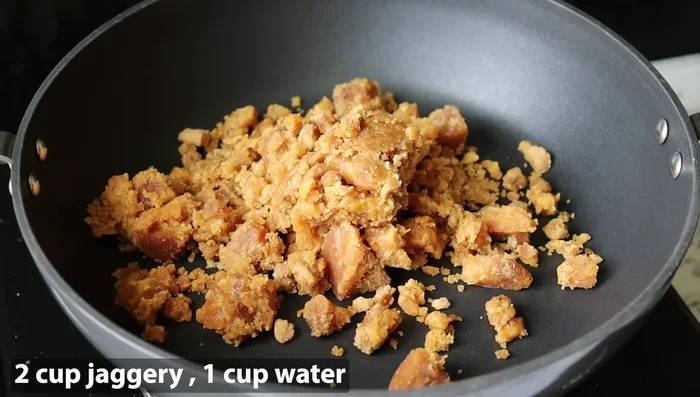 In a pan, add 2 cups of jaggery and 1 cup of water. Heat on high flame until the jaggery dissolves completely.