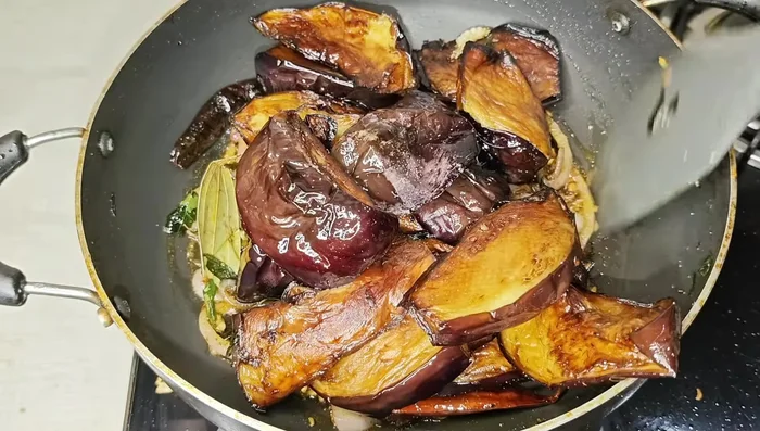 Add the fried brinjals to the spiced onions. Gently stir to combine, ensuring not to mash them. Fry for a few minutes until the spices and brinjals are well combined.