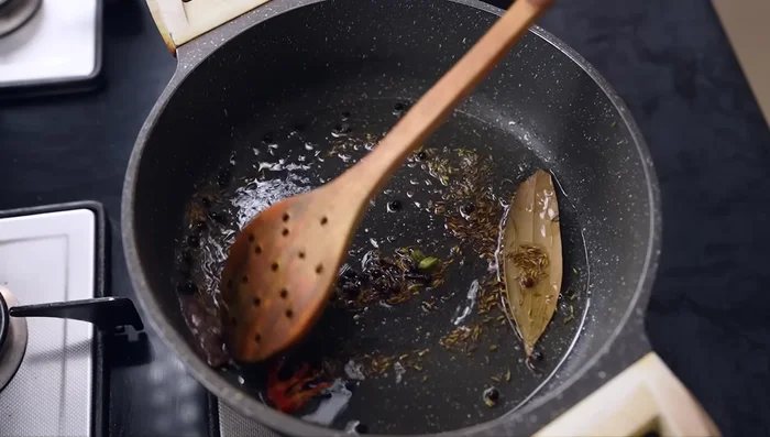 Once the spices start to splutter, add the sliced onions and cook until lightly golden brown.