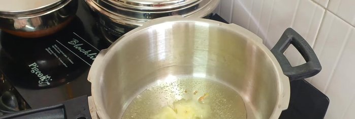 Heat ghee in a pressure cooker. Add cumin seeds, asafoetida, fennel seeds, cardamom, and bay leaves; sauté briefly.