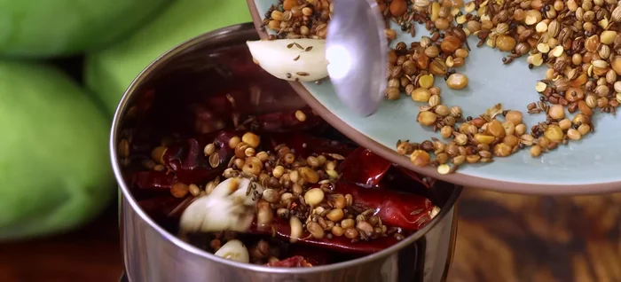 Grind chutney: In a mixer jar, add roasted red chilies, roasted dal and spices, salt, and turmeric powder. Grind to a coarse mixture. Add half the mango cubes and pulse. Add remaining mangoes and pulse until well blended but slightly chunky.