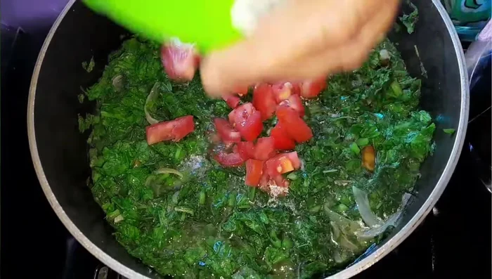Add the chopped tomato and continue cooking until the spinach herbs are cooked through.