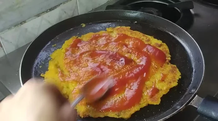 Spread ketchup (or other sauces) on the pancake. Layer the paneer stuffing on top. Cover and cook.