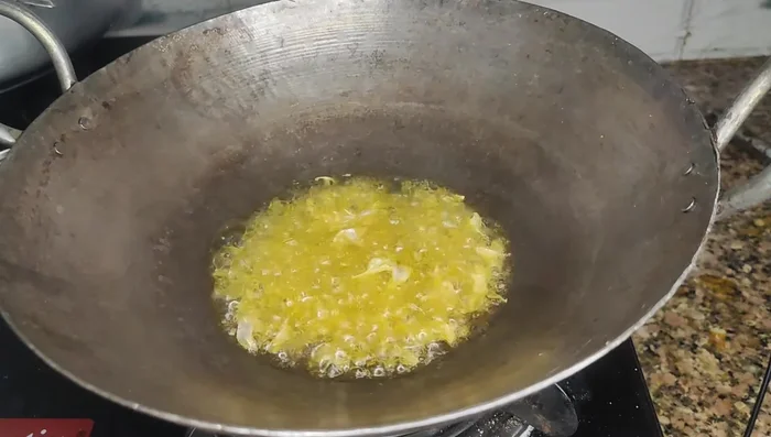 Heat mustard oil in a pan. Add crushed garlic, cumin seeds, and asafoetida. Sauté until the garlic is lightly browned.