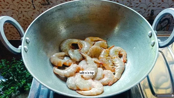 Heat 1 tablespoon of mustard oil in a pan. Add the prawns, 0.5 teaspoon salt, 0.5 teaspoon turmeric powder, and 0.25 teaspoon chili powder. Fry until the water dries completely (about 8-10 minutes), stirring occasionally.