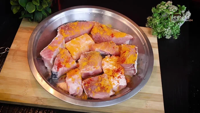 Marinate the fish with 1 spoon of turmeric powder, 1/2 teaspoon red chili powder, salt to taste, and 2 spoons of mustard oil. Mix well and set aside for 15-20 minutes.