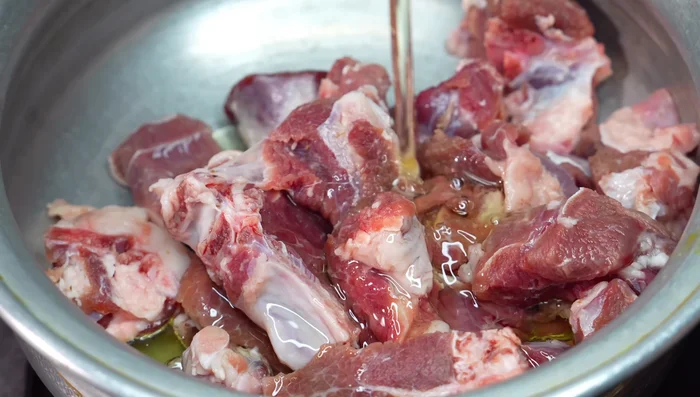 Heat oil in a kadhai or large pan. Add mutton, salt, cardamoms, and cinnamon. Fry on high flame for 5-6 minutes until browned.