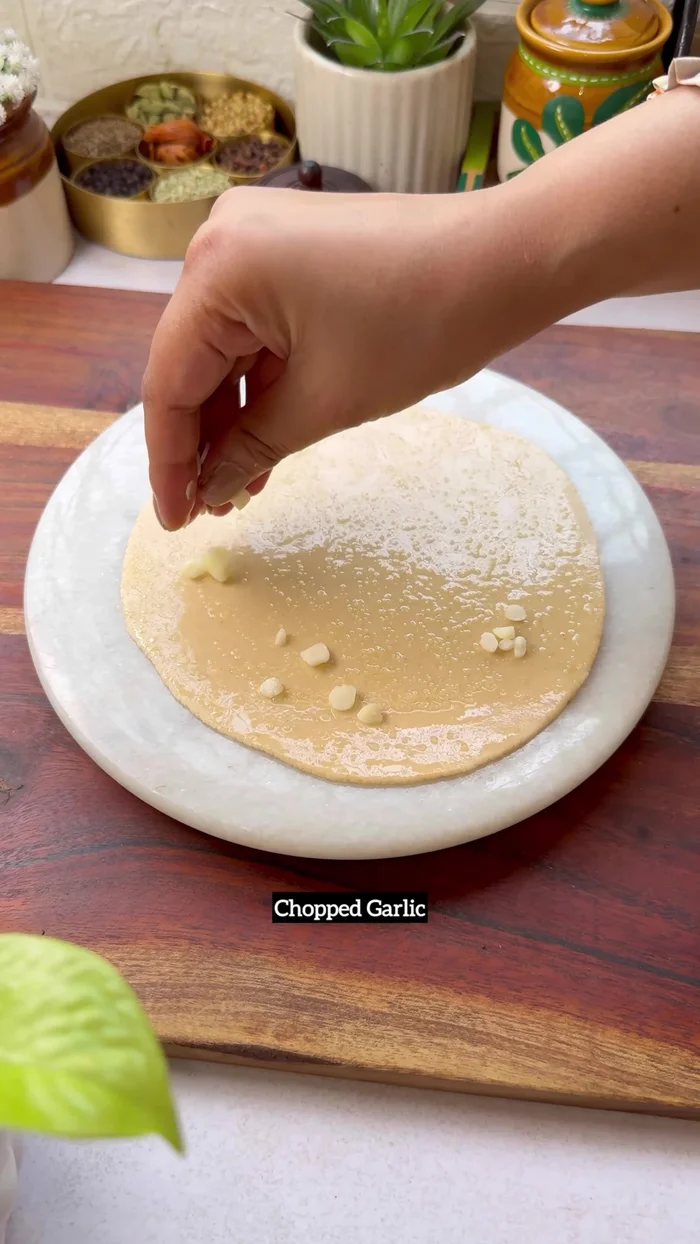 For Chilli Cheese Garlic Paratha: Roll out roti dough, spread ghee and salt. Add chopped garlic, spring onions, green chilies, chili flakes (optional), mozzarella cheese, and coriander leaves. Fold and roll. Cook for 5 minutes per side with ghee.