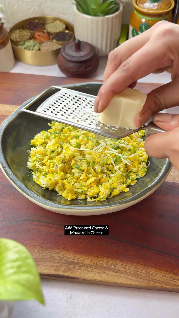 For Corn Cheese Paratha: Grate corn, garlic, green chilies, and coriander leaves. Mix with processed cheese, mozzarella cheese, basic spices, salt, and Maggi masala. Roll out roti dough, fill with mixture, fold, and shape into a paratha. Cook for 5 minutes per side with ghee or butter.
